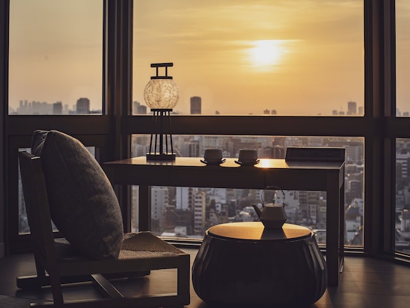 Habitació moderna amb vista a la ciutat, una taula amb dues tasses, una làmpada i una cadira.