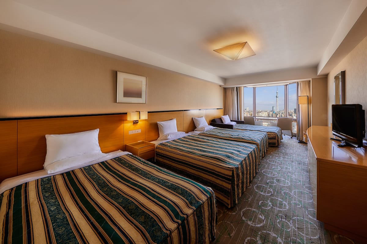 A hotel room with two beds, a TV, and a city view.