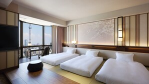 Habitación de hotel con dos camas, televisión, escritorio y vista a una torre.