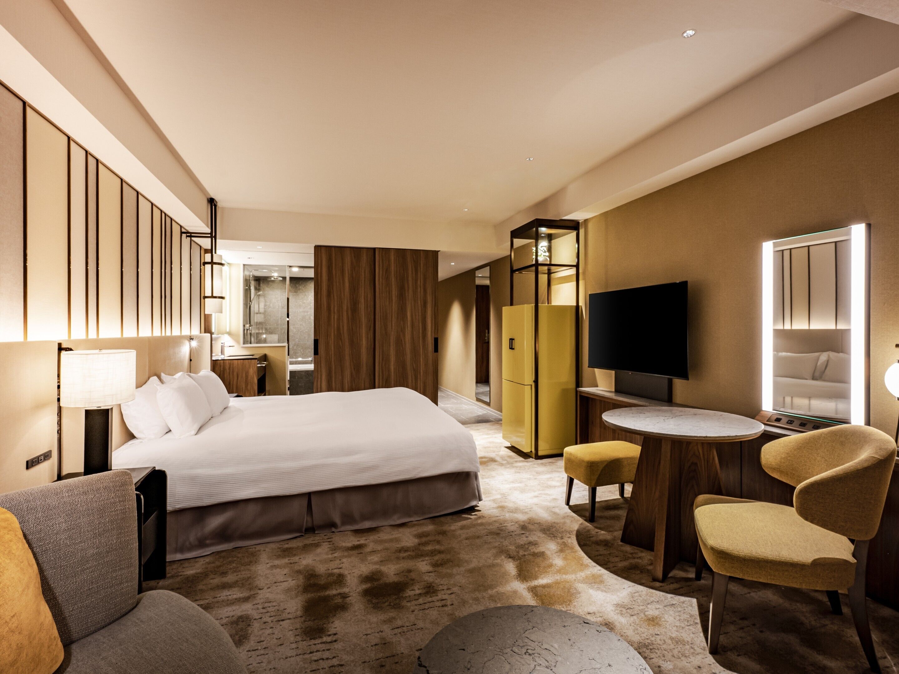 A hotel room with a bed, a TV, a desk, a chair, a wardrobe, and a bathroom.
