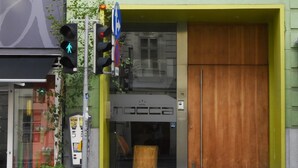 Un bâtiment à la façade verdoyante, doté d’une grande porte en bois et d’une fenêtre située au-dessus de la porte.