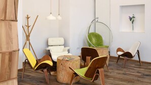 Un salon moderne avec un plancher en bois, un canapé blanc, un fauteuil vert, une table basse en bois et un fauteuil suspendu.