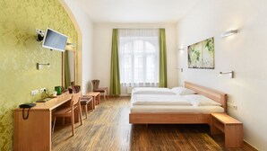 Une chambre d’hôtel équipée d’un lit, d’un bureau, d’une chaise, d’une télévision et d’une fenêtre avec des rideaux.