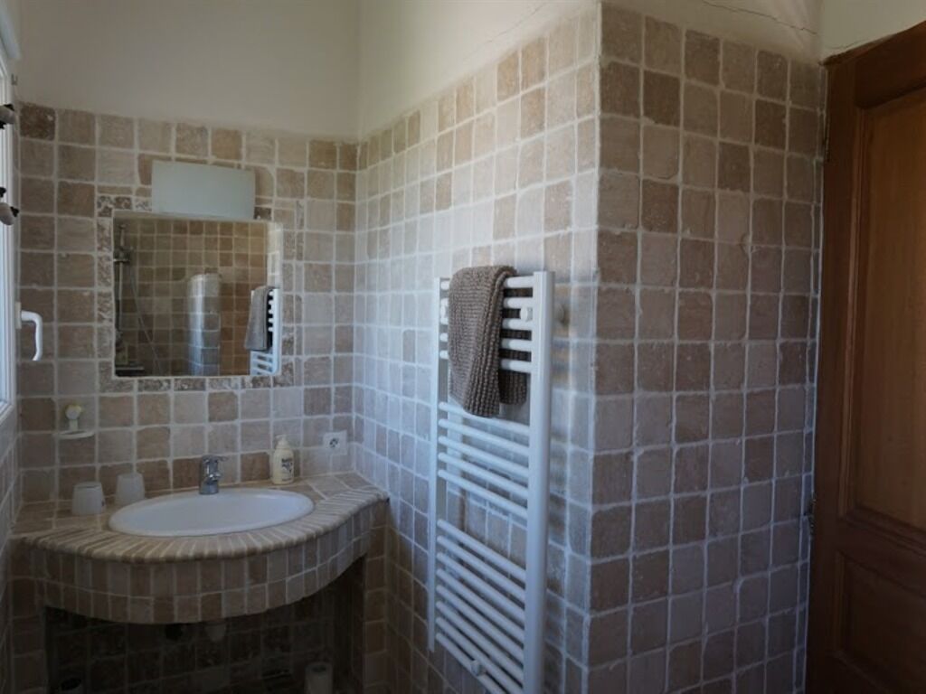 A bathroom with a sink, mirror, towel rack, and a shower area.