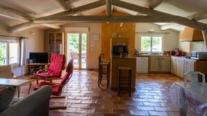 A spacious living area with a kitchen, wooden beams, tiled flooring, and a television. - La Buisse (Simiane-la-Rotonde)
