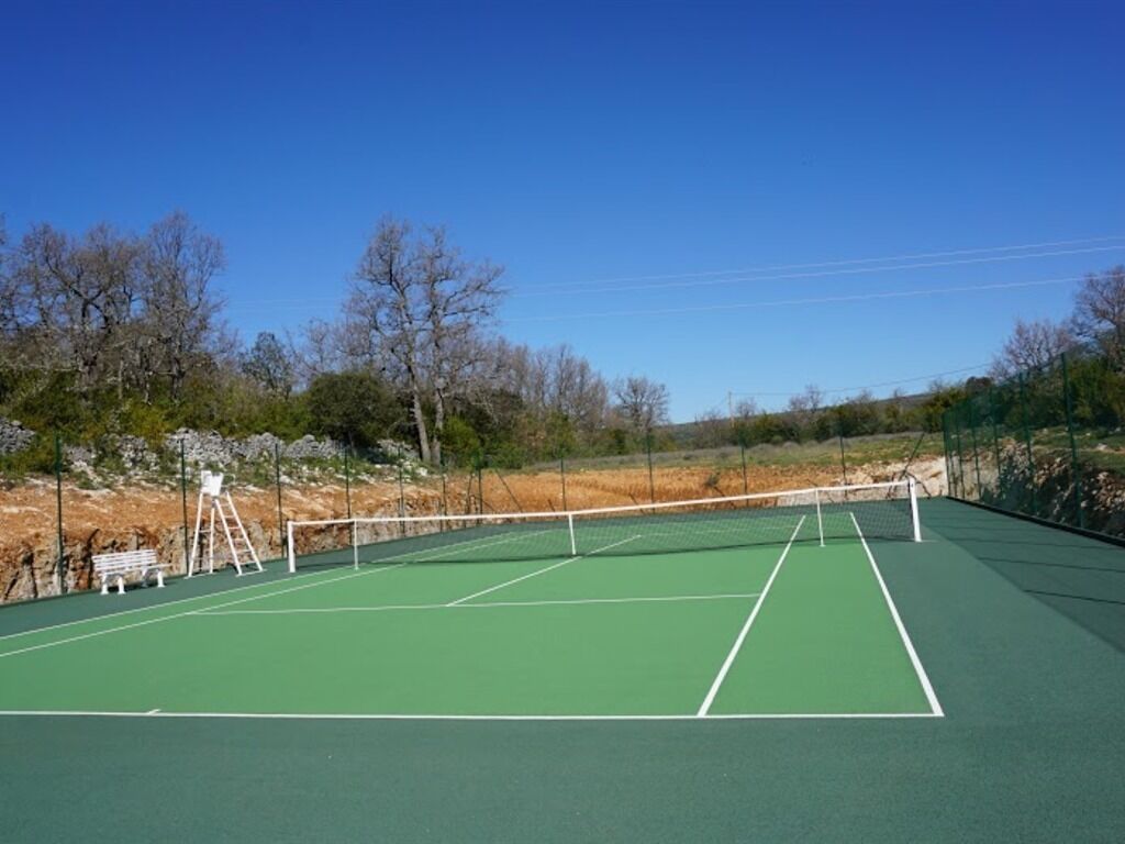 A tennis court with a net, benches, and a ladder.
