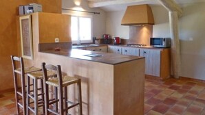 A kitchen with a central island, bar stools, wooden beams, and basic appliances. - La Buisse (Simiane-la-Rotonde)