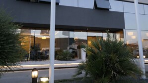 A modern building with large windows, outdoor seating, and well-lit pathways. - Hotel Leone (Citluk)