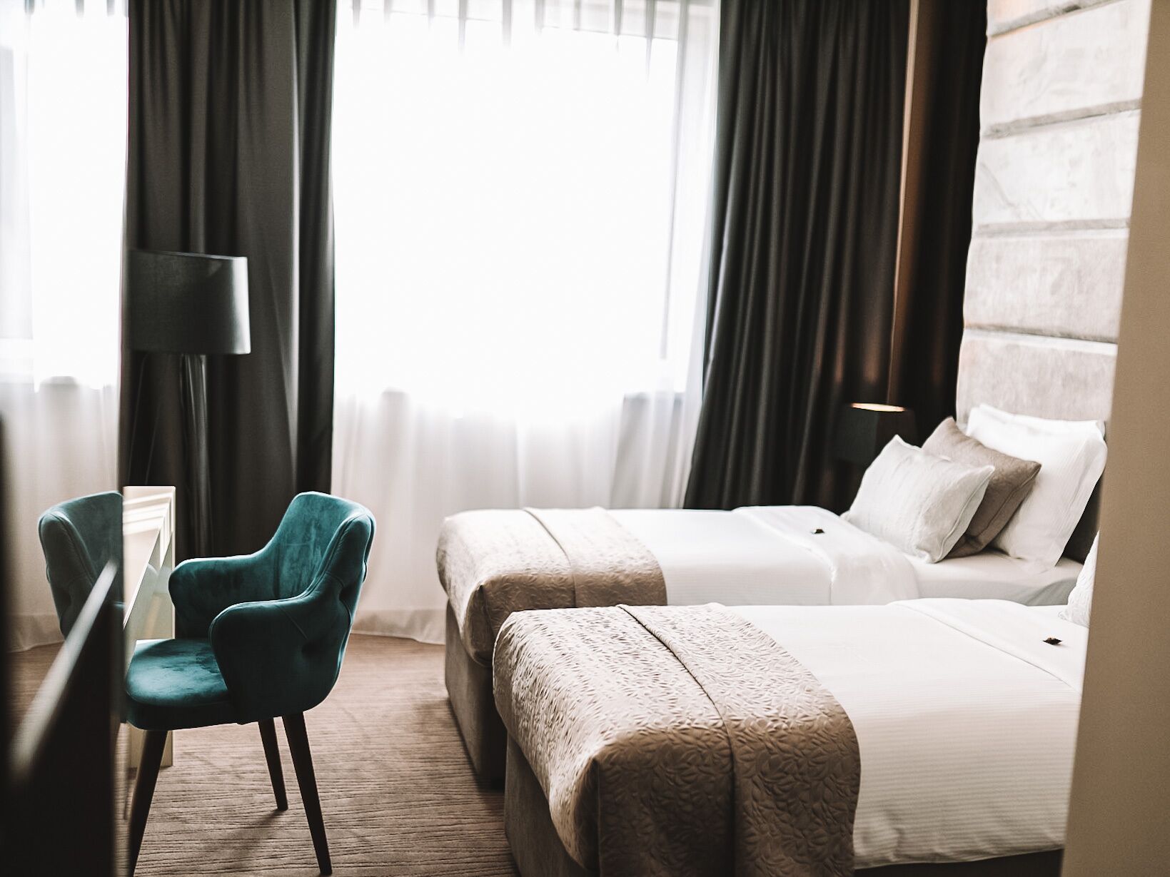 A hotel room with two beds, a desk, and a chair.