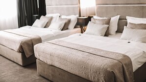 A hotel room with two beds, a large window with curtains, and a bedside table with a lamp. - Hotel Leone (Citluk)
