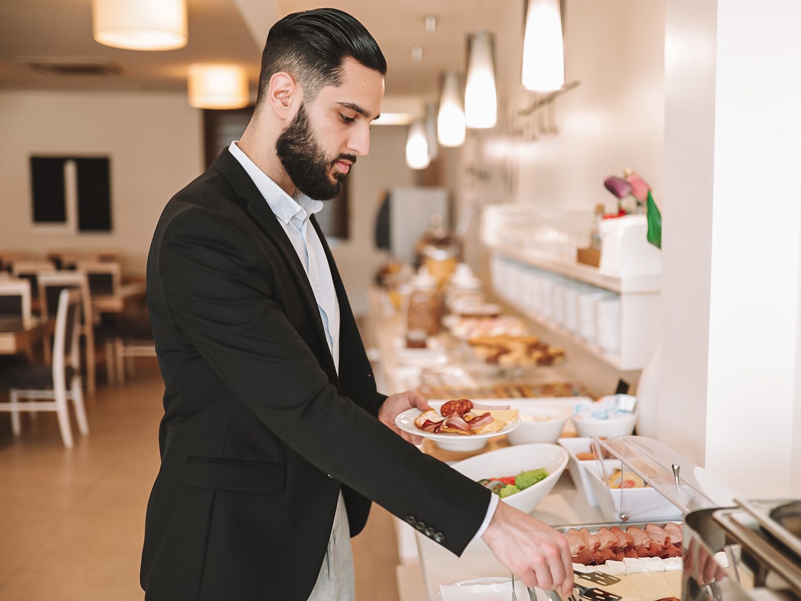 A buffet setup with various food items and a person serving food.