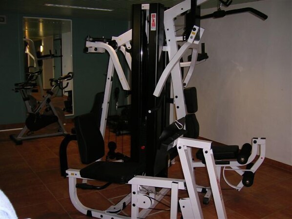 Une salle de sport équipée de divers appareils d’entraînement, notamment un banc de développé couché et un support à squats.