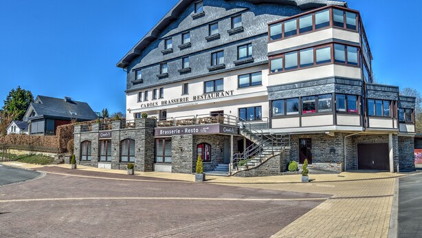 Un edificio de restaurante de varios pisos con fachada de piedra y diseño moderno.
