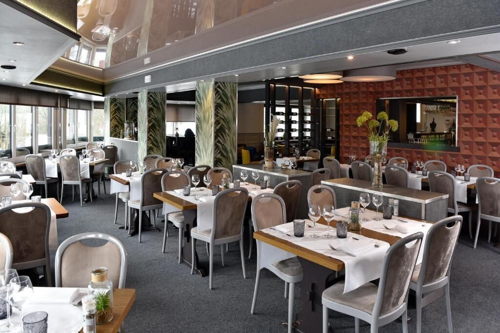 A restaurant with multiple dining tables, chairs, and a bar area.