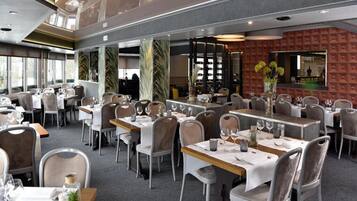 A restaurant with multiple dining tables, chairs, and a bar area.