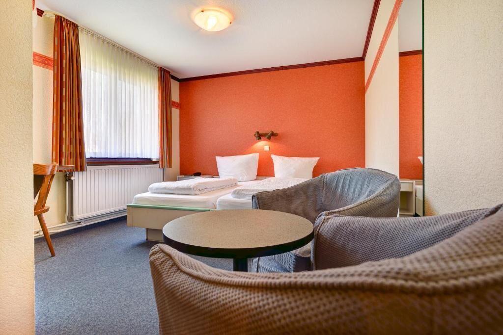 A hotel room with a bed, a round table, and a chair.