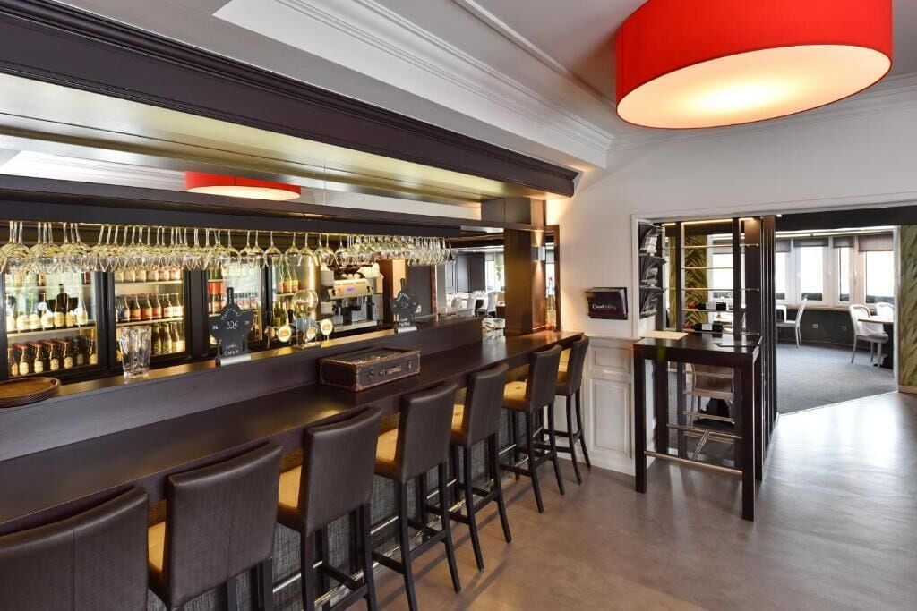 Un espace bar doté d’un long comptoir, de nombreux tabourets et d’une variété de bouteilles et de verres.