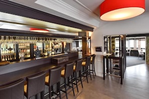 A bar area with a long counter, multiple bar stools, and a variety of bottles and glasses. - Hôtel du Lac (Buetgenbach)