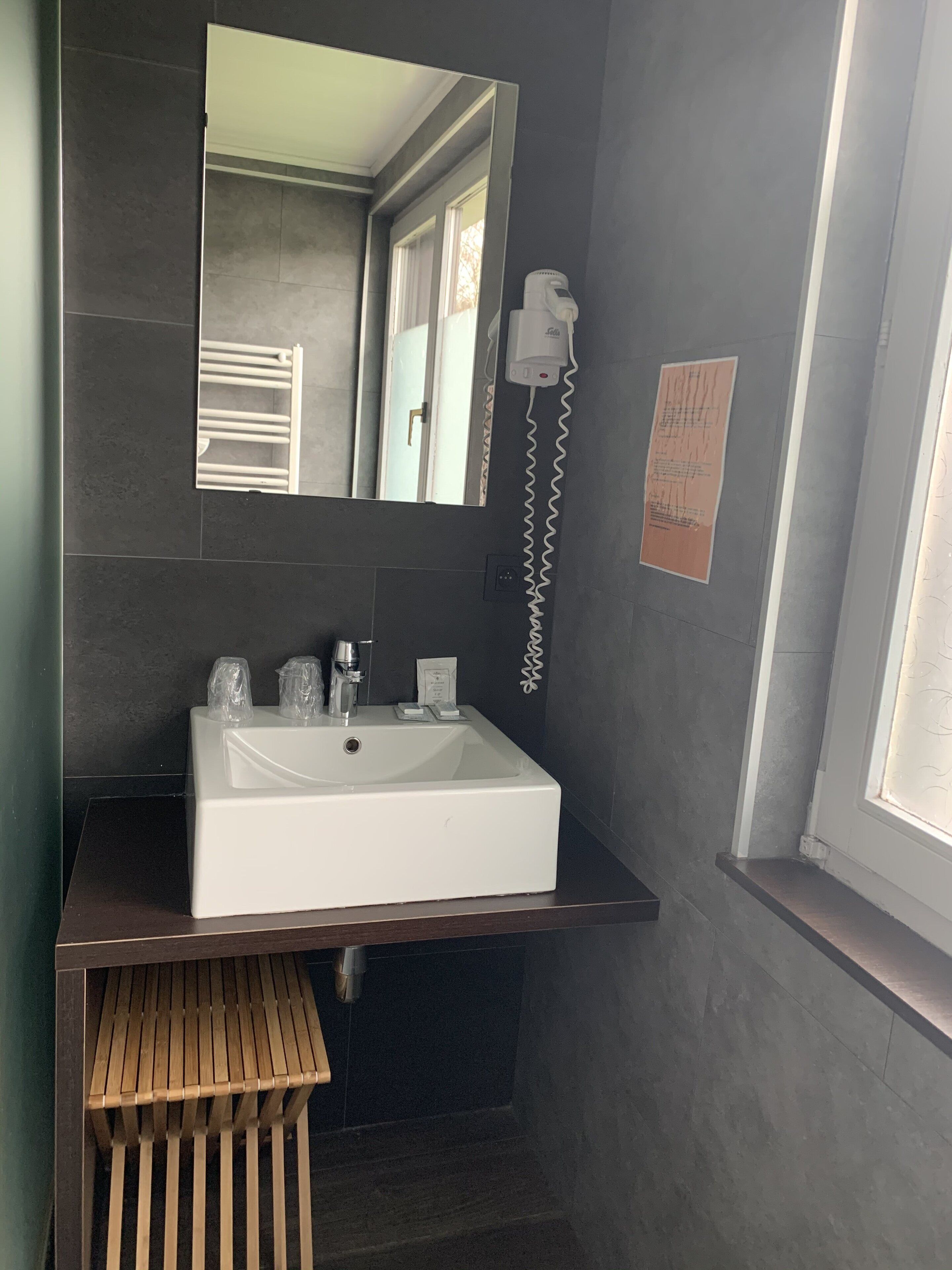 A modern bathroom with a white sink, a mirror, and a towel rack.