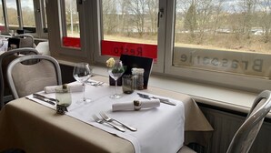 Una mesa de comedor dispuesta con mantel blanco, copas de vino, cubiertos y un centro de mesa floral.