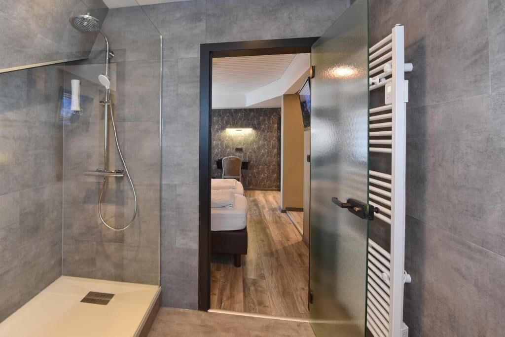 Un baño moderno con ducha envuelta en vidrio, bañera blanca y un perchero para toallas.