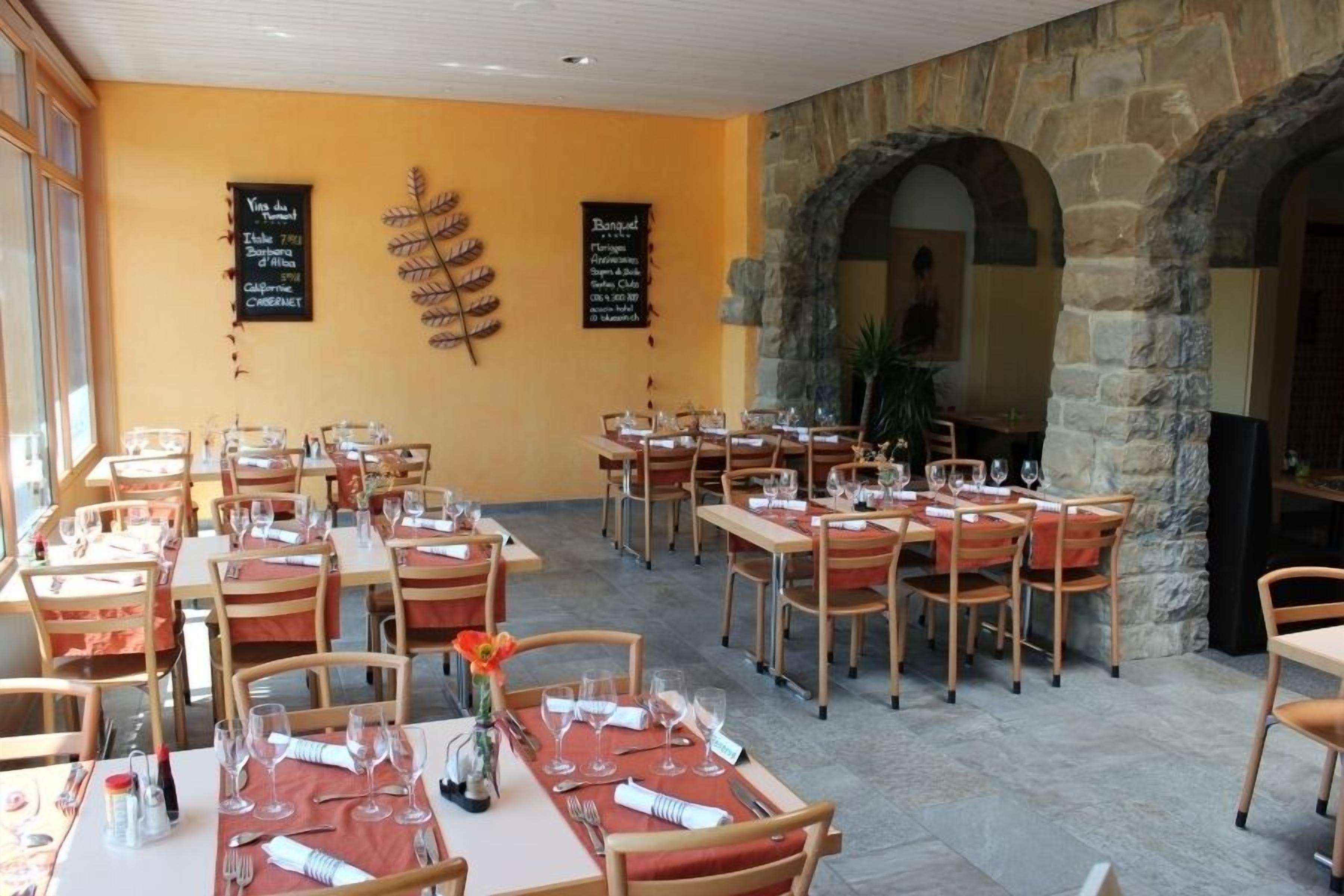 Un restaurant doté de nombreuses tables et chaises, d’arches en pierre et de tableaux noirs affichant les plats à la carte.