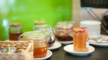 A table with various food items, including jars of preserves and a basket of bread.