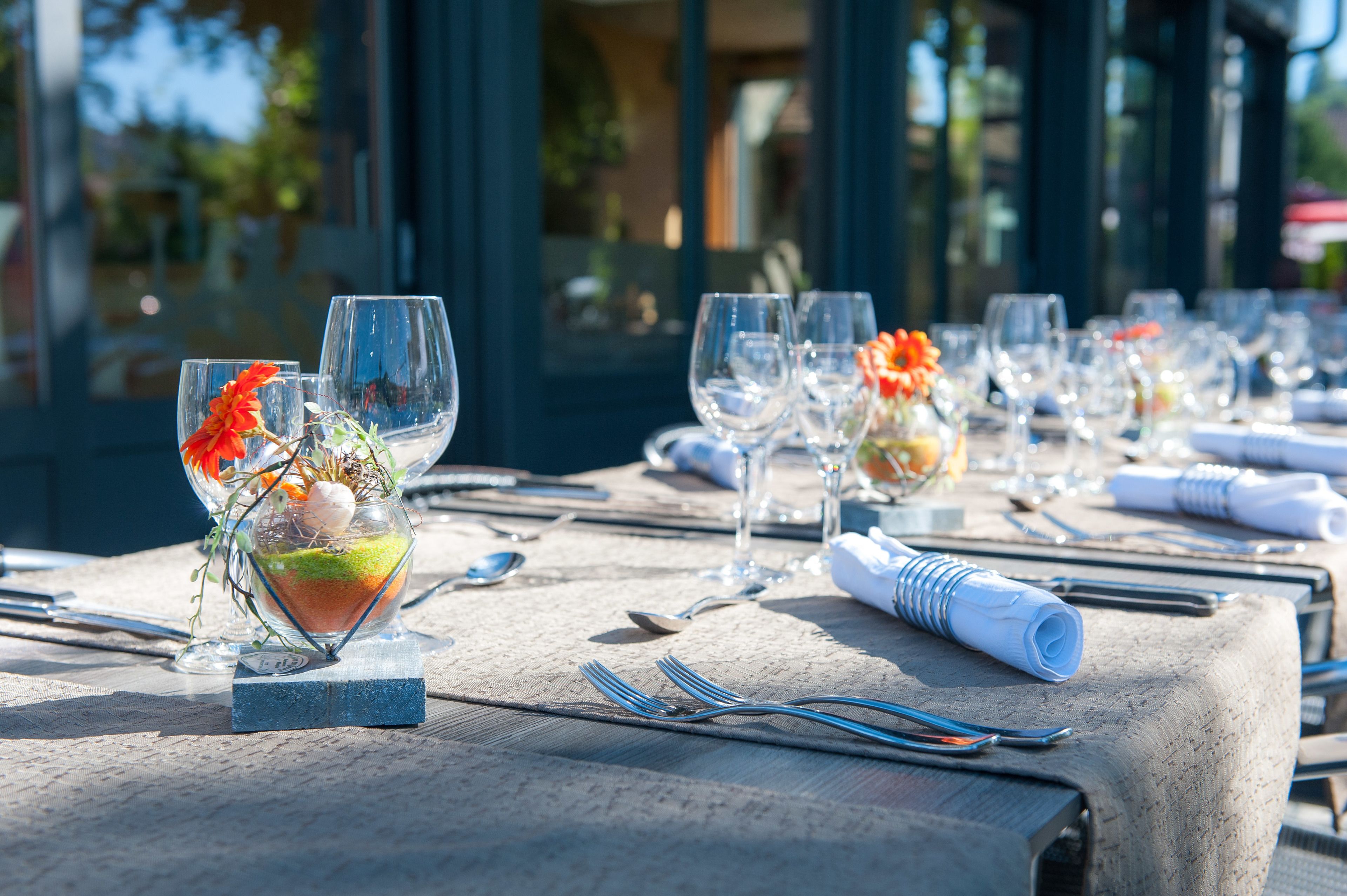 Una mesa dispuesta para una comida, con varias copas de vino, un pequeño arreglo floral y servilletas dobladas con cuidado.
