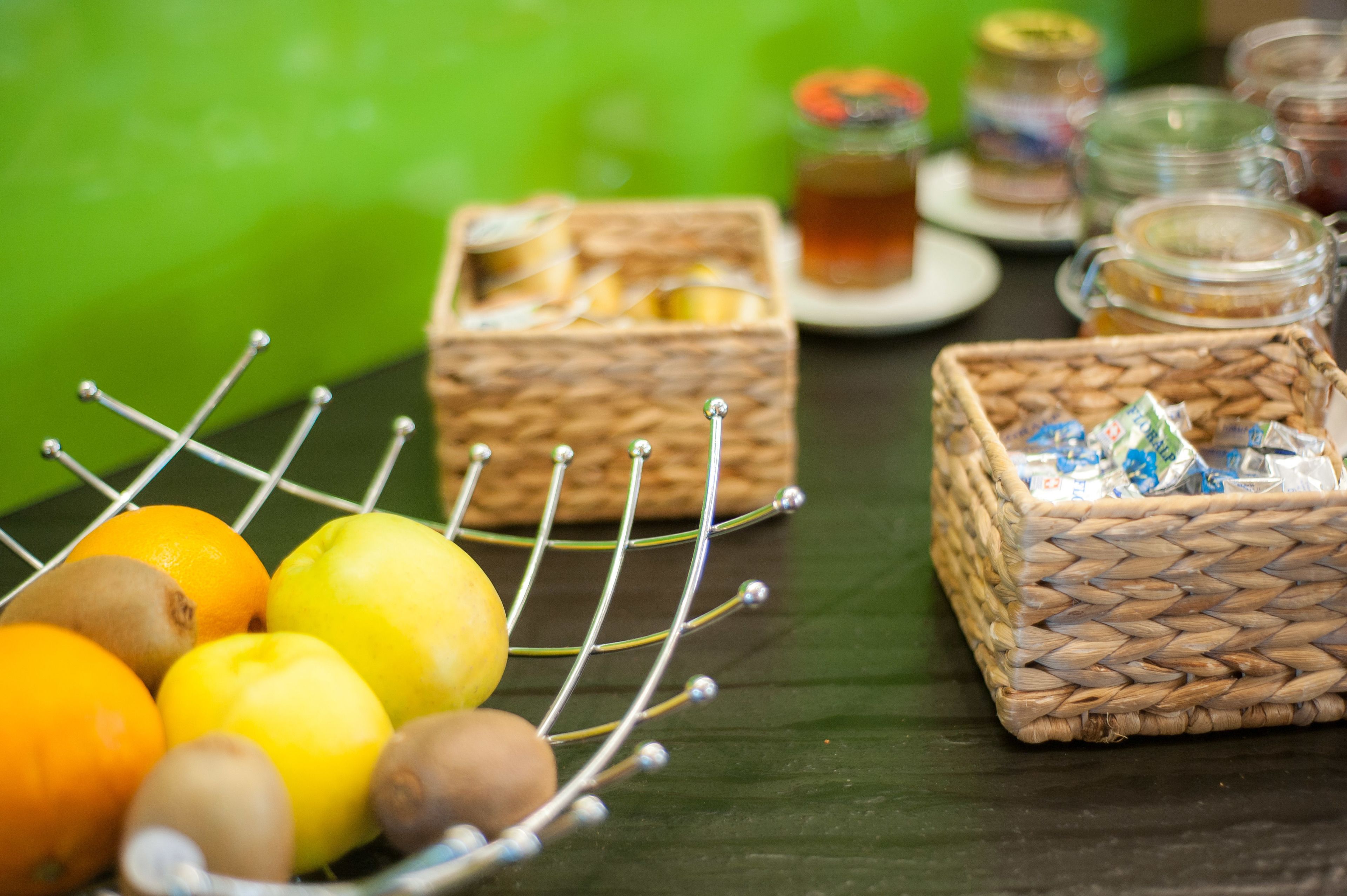 A table with wicker baskets containing fruits and jars of honey.