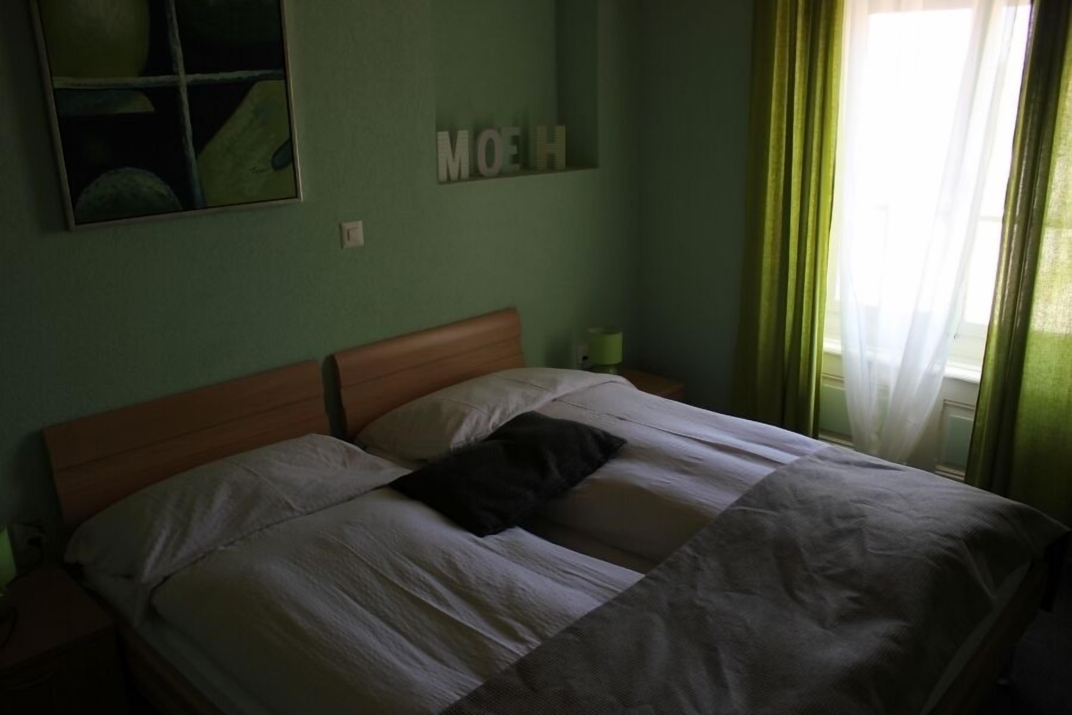 Ein Schlafzimmer mit einem Doppelbett, einem Nachttisch, einem Spiegel und einem an der Wand befestigten Schild.