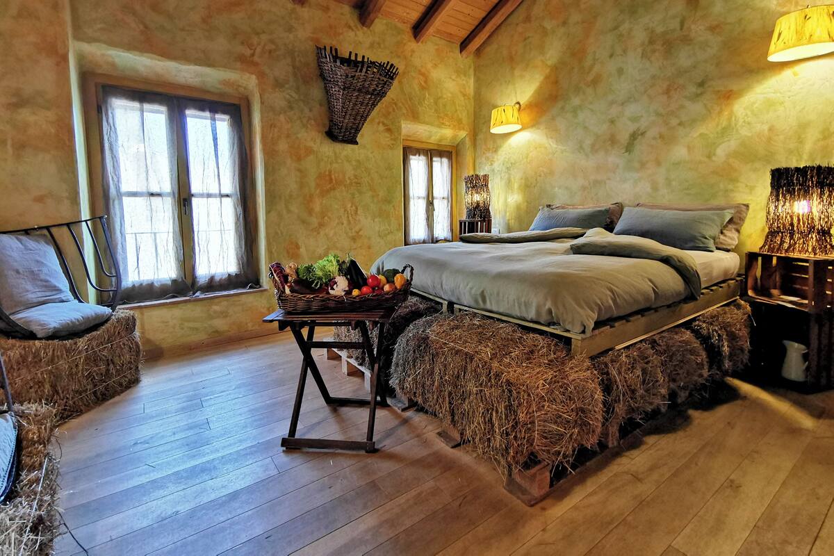 A rustic bedroom with a wooden bed, a wicker basket with fruits, and a rustic lamp.