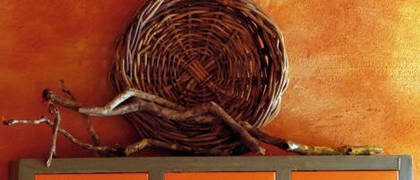 A wicker basket on a wall with branches.