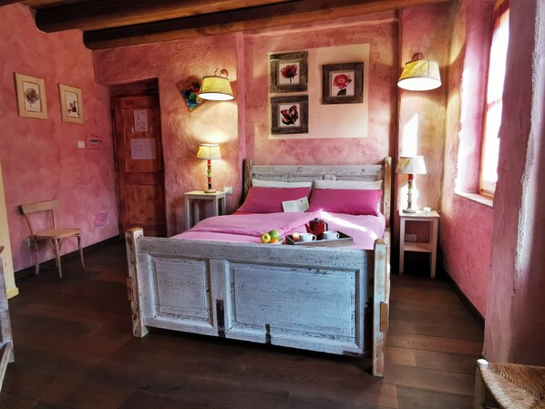 Un dormitorio acogedor con cama de madera, paredes rosas y suelo de madera.