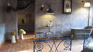 A rustic room with a bed, a table with chairs, a bathtub, and decorative wall sconces. - Galbusera Bianca  (La Valletta Brianza)