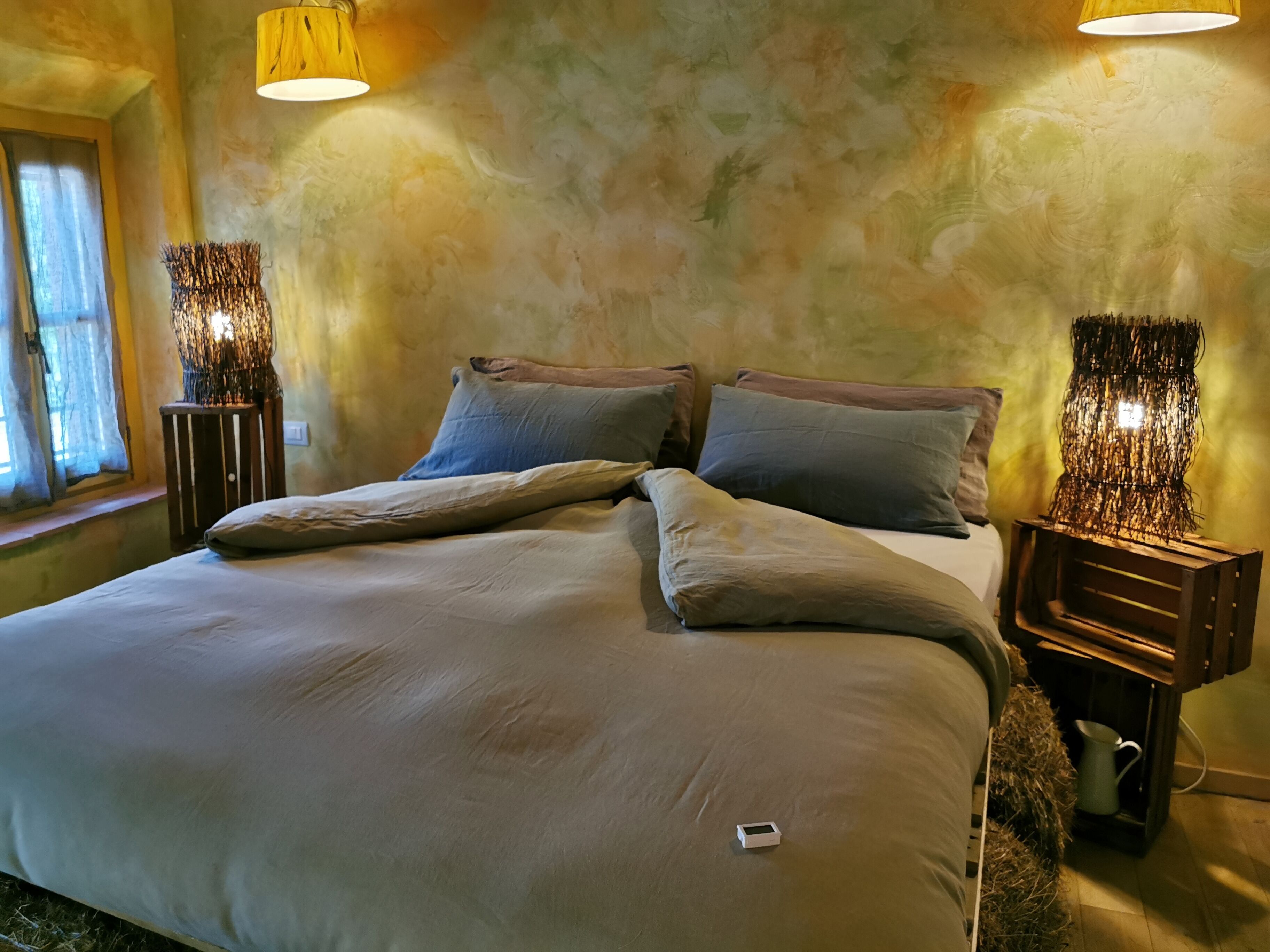 Ein Bett mit einer beigen Bettdecke und Kissen, zwei Nachttische mit dekorativen Lampen und eine strukturierte Wand.