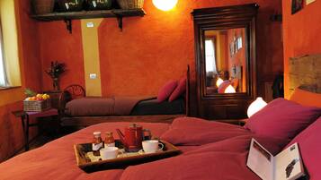 Une chambre confortable avec un lit, une table de chevet sur laquelle se trouve un plateau avec des articles pour le petit-déjeuner, un miroir et une étagère avec des bouteilles et des paniers.