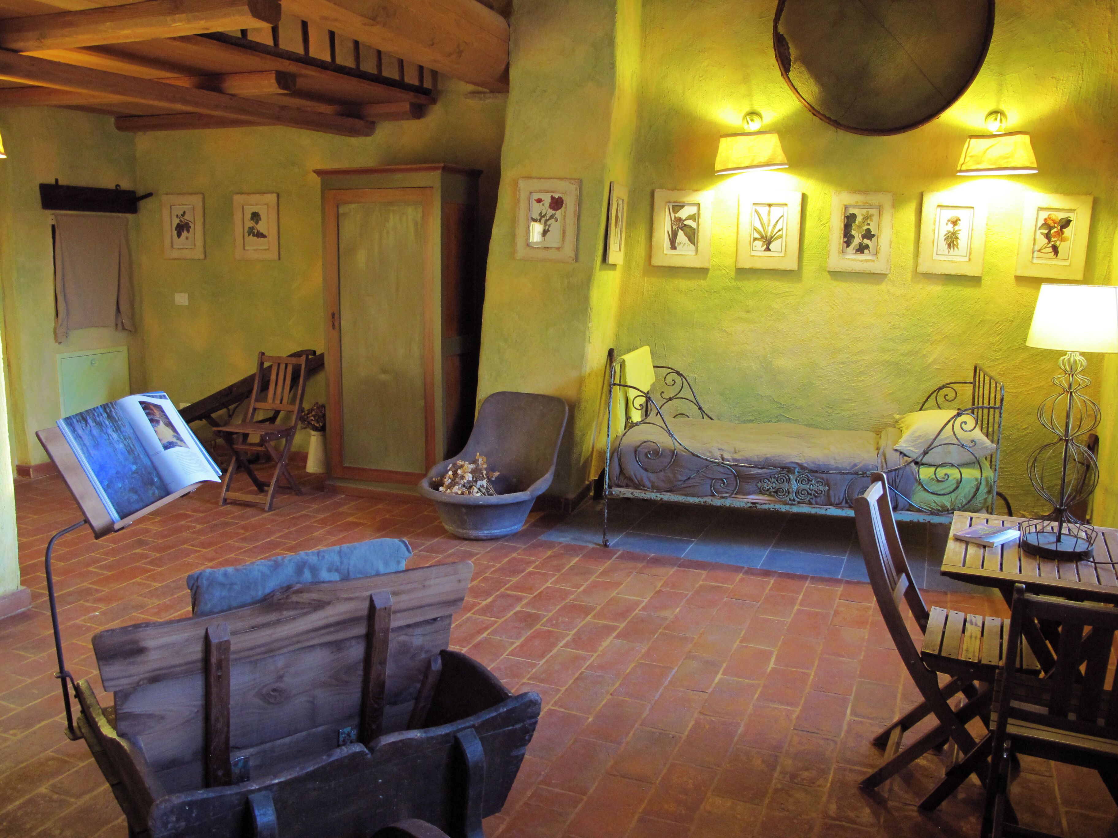 A rustic room with a bed, a chair, a table, and a wooden cart.