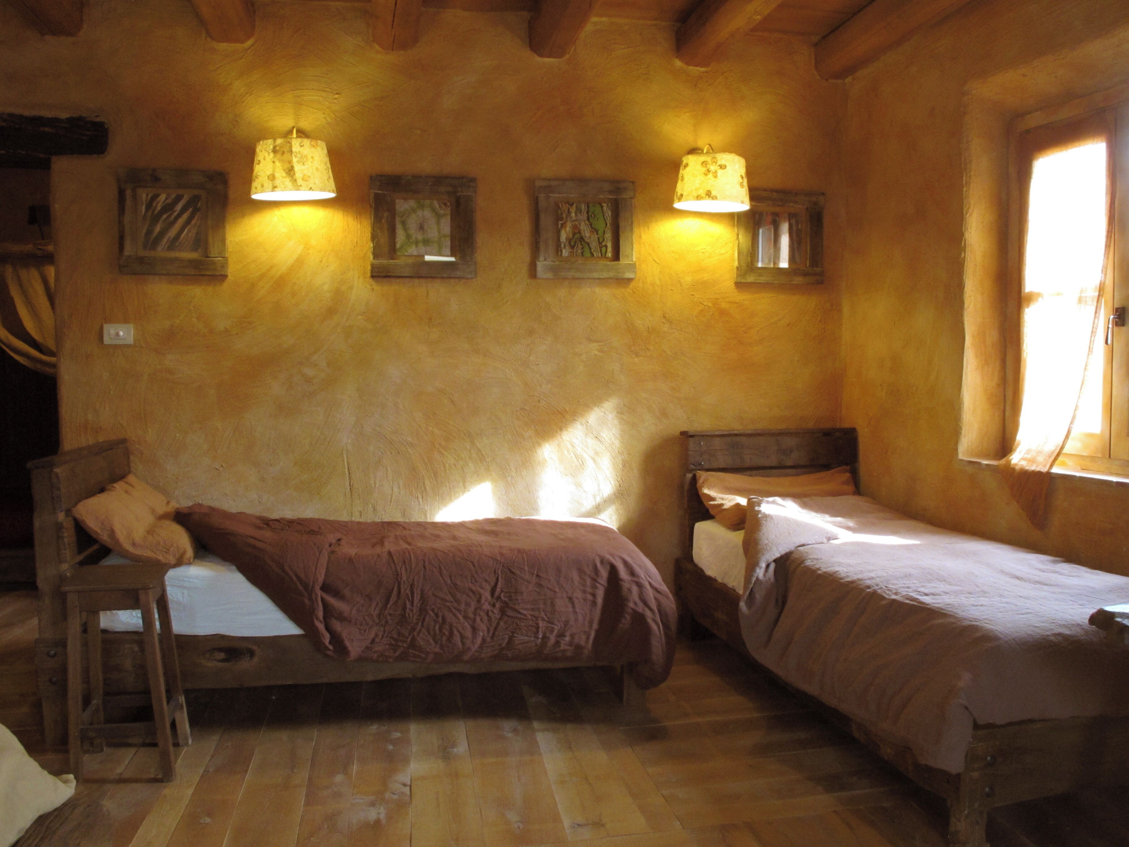 A cozy room with two wooden beds, a wooden chair, and a window with curtains.