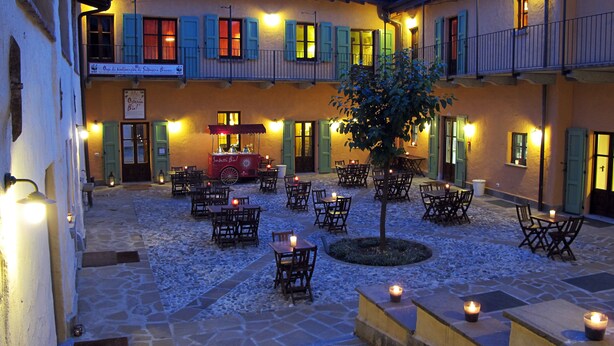 A courtyard with stone flooring, outdoor seating, and a food cart. - Galbusera Bianca  (La Valletta Brianza)
