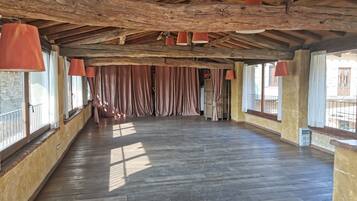 A spacious room with wooden floors, large windows, and red hanging lamps.
