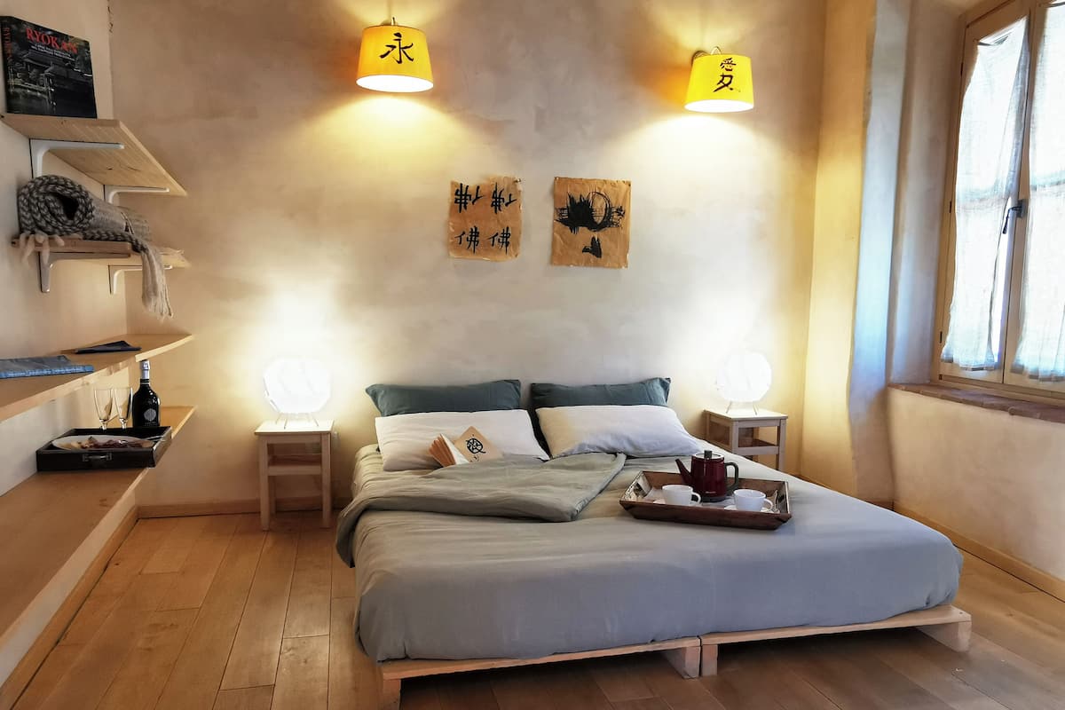 A neatly arranged bedroom with a bed, bedside tables, and a window.