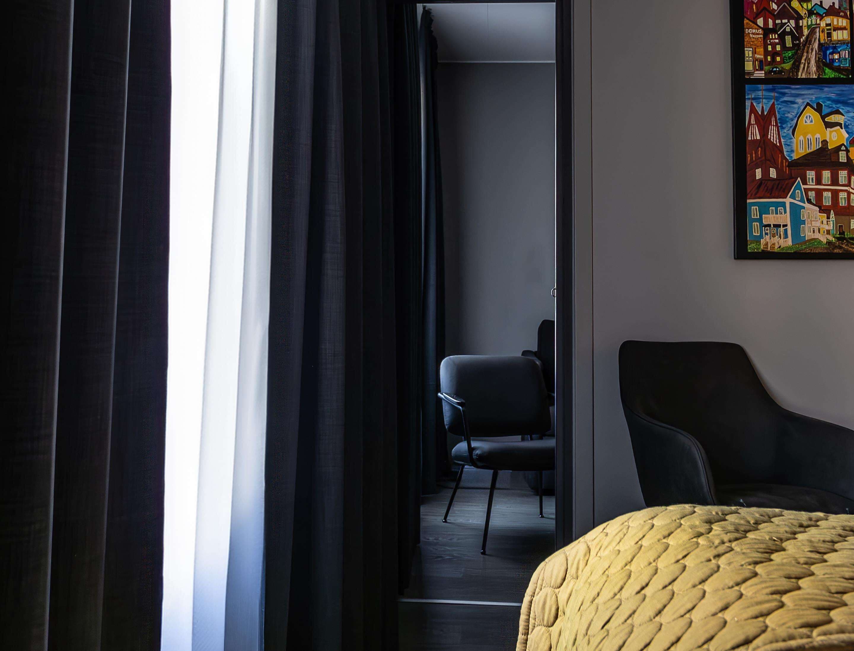 Una habitación de hotel con una cama, una silla y un cuadro en la pared.