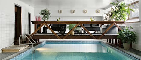 Una piscina interior con cubierta de madera y plantas en macetas.