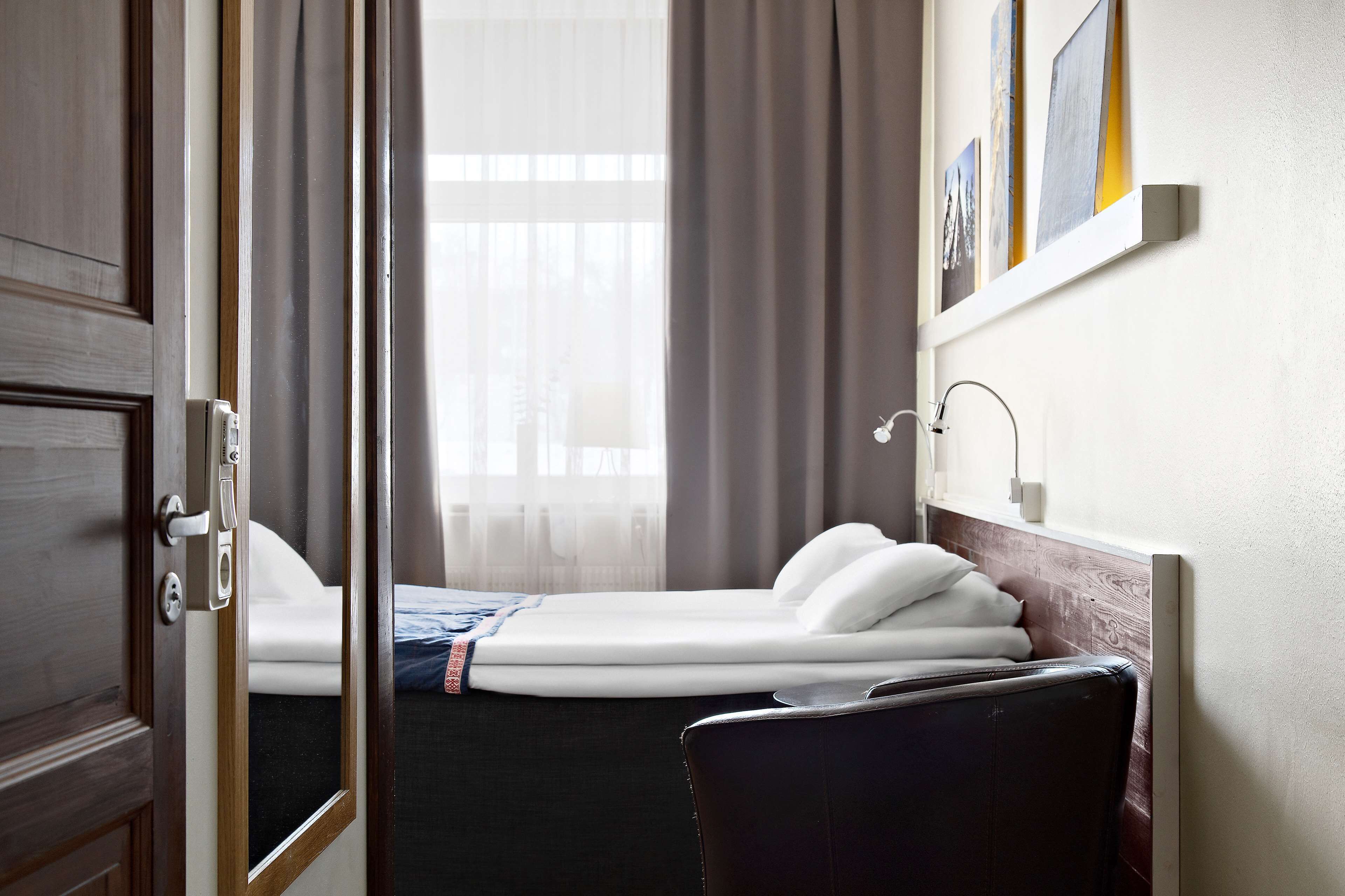 Una habitación de hotel con cama, escritorio y ventana con cortinas.