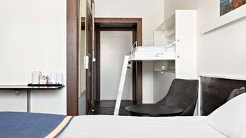 A hotel room with a bunk bed, a desk with a chair, and a small table with a tray of items.