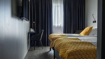 Une chambre d’hôtel avec deux lits, un bureau, une chaise et un téléviseur fixé au mur.