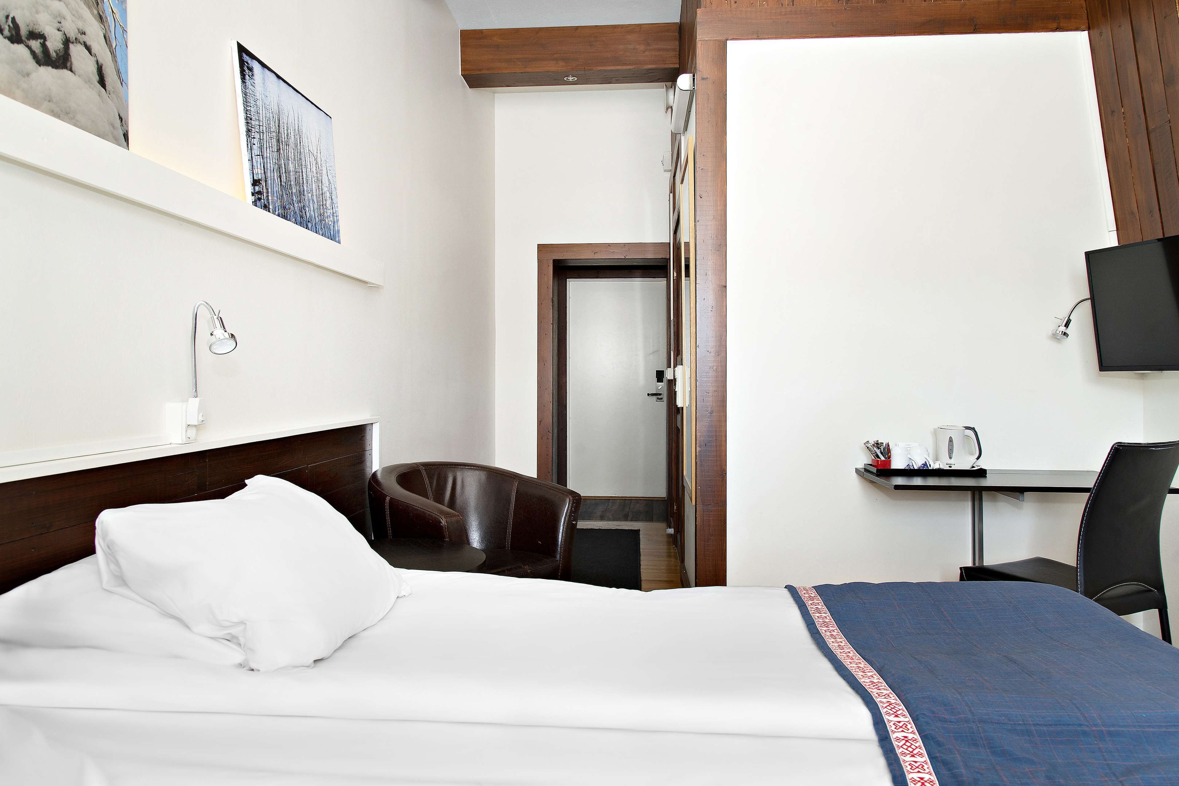 Habitación de hotel con cama, escritorio, silla y televisor.