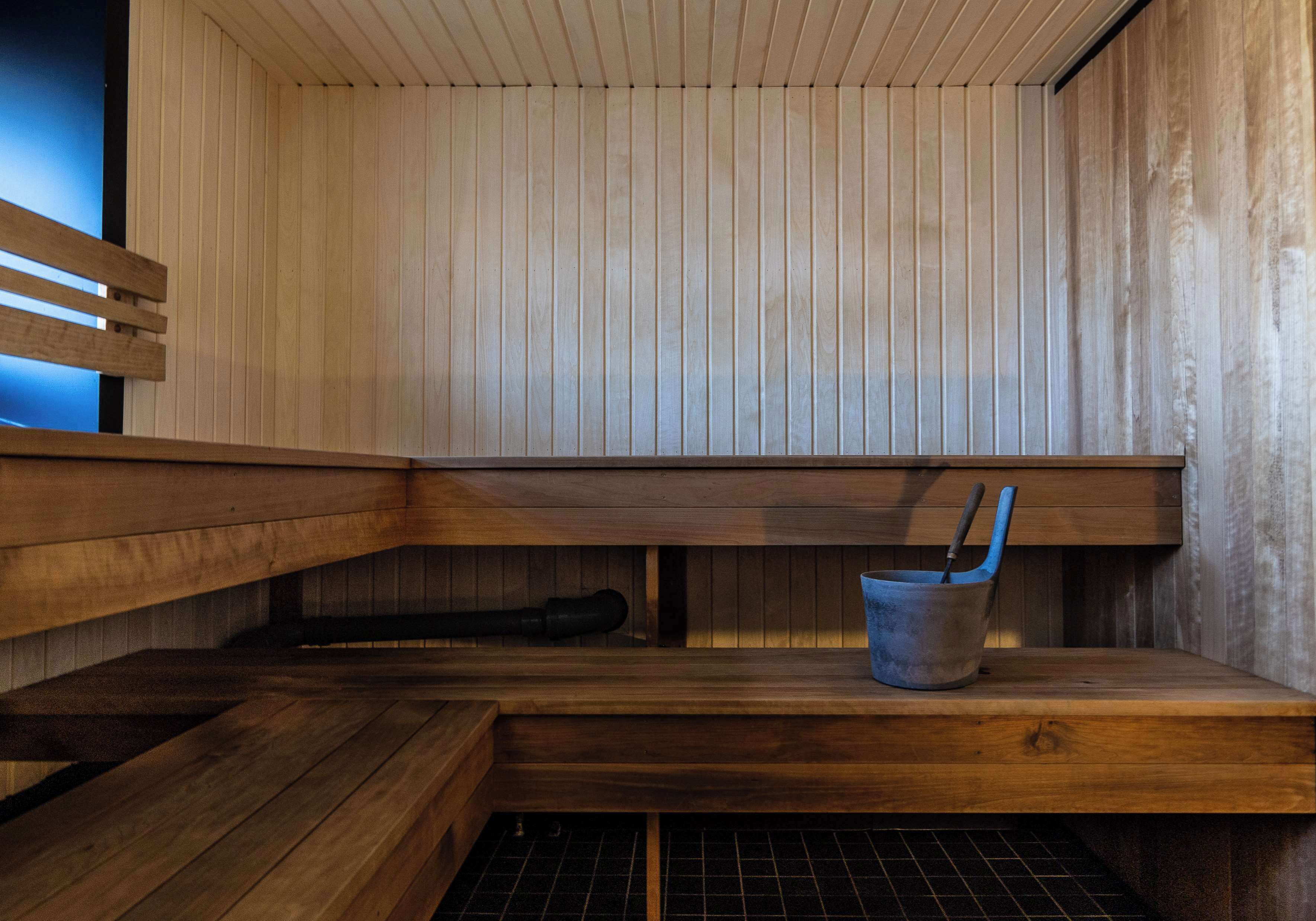 Una sauna con bancos de madera y un cubo de metal.