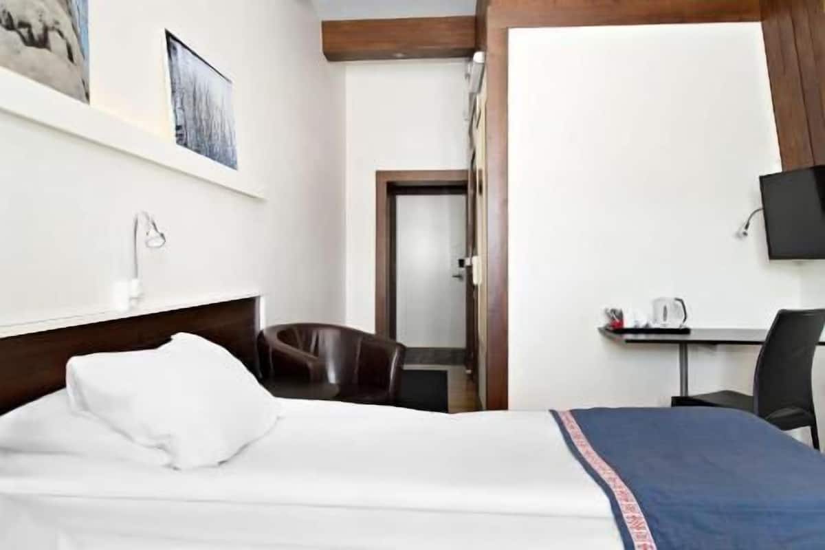 Ein Hotelzimmer mit Bett, Schreibtisch, Stuhl, Fernseher und einer Tür.