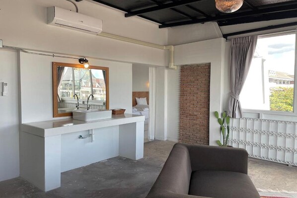 Casa de banho moderna com toucador branco, espelho grande e parede de tijolos integrada.